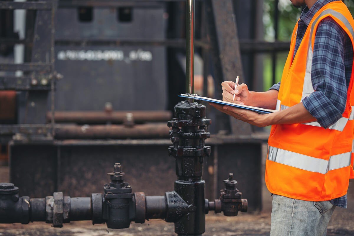workers standing checking beside working oil pumps 1 1