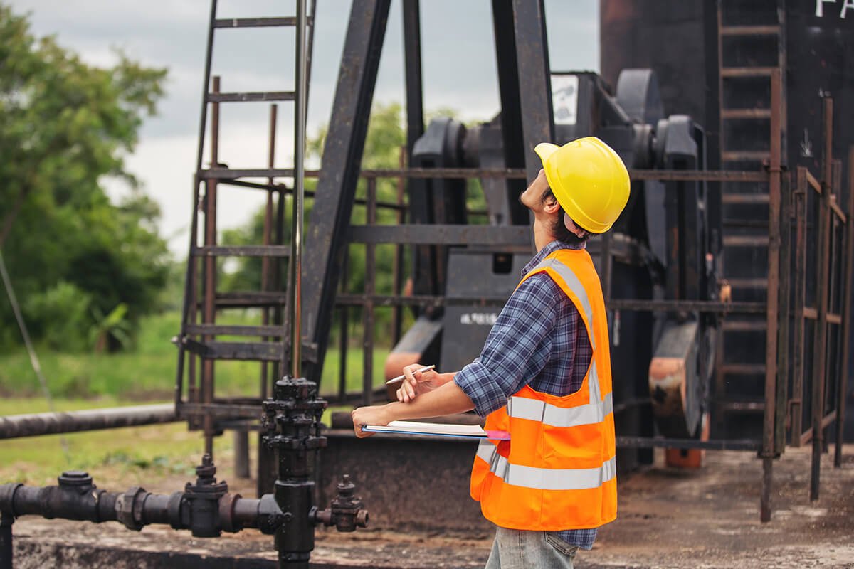 workers standing checking beside working oil pumps 2